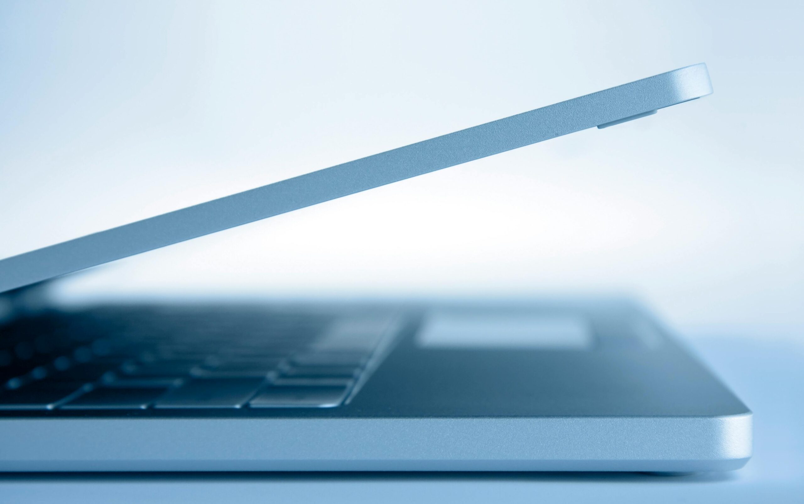 Profile view of a sleek modern laptop in a minimalist style, highlighting its slim design and technology focus.